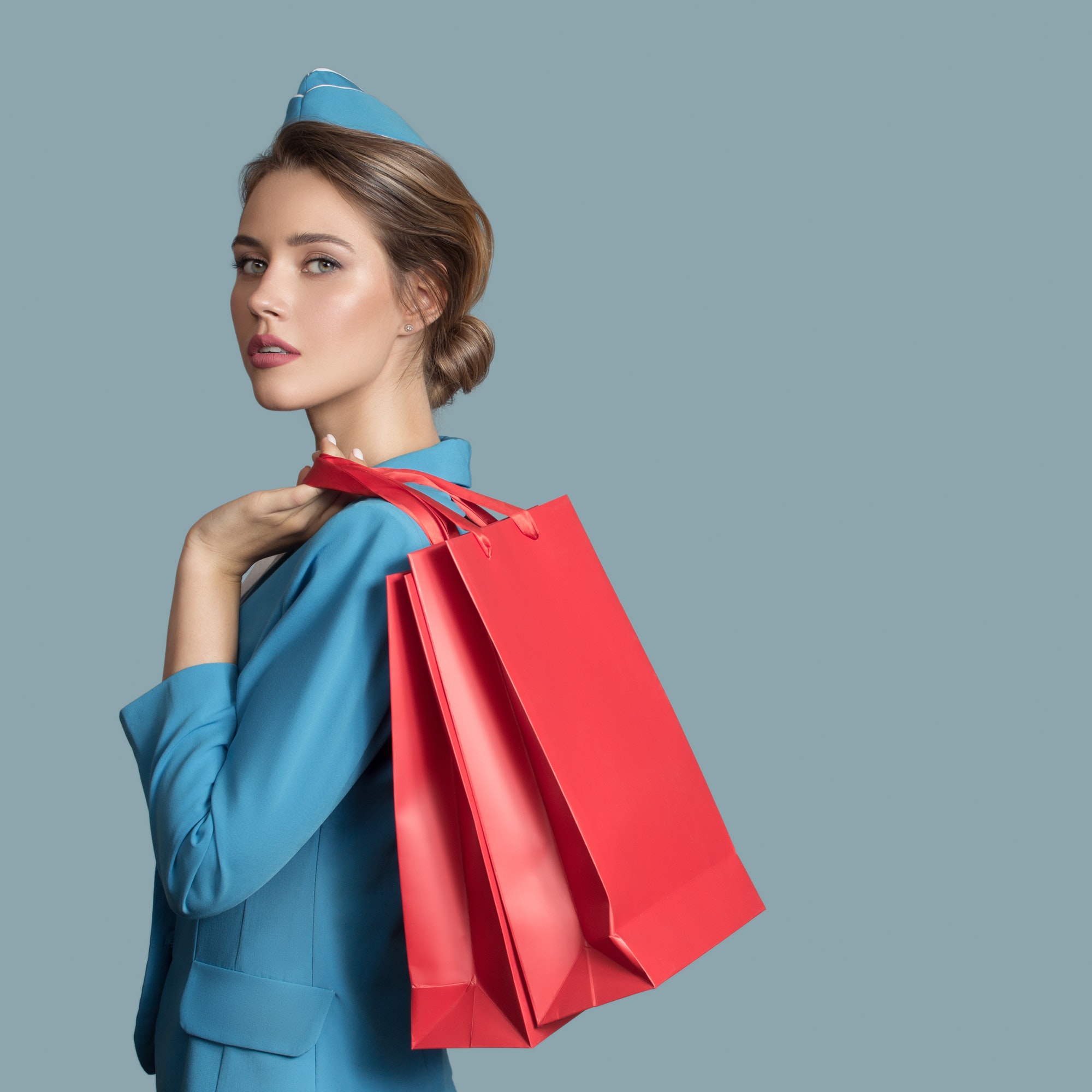 Attractive Stewardess Holding Red Shopping Bags. Duty Free.