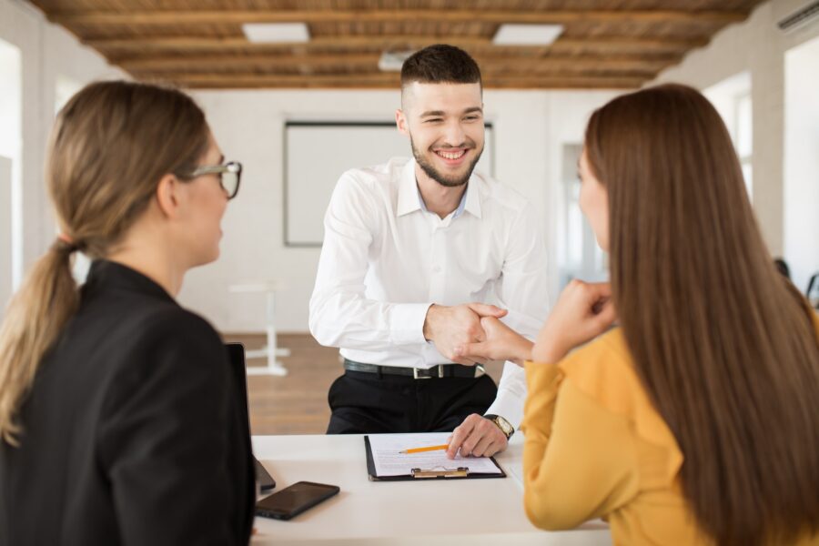 Cheerful male applicant happily shaking employer hand. Young man