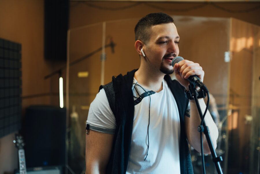 man singing into a microphone in musical rehearsal studio