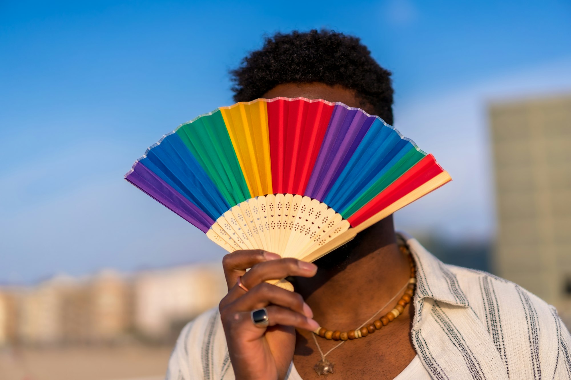 Colorful rainbow fan during gay pride, LGBT collective fan, unrecognizable man with fan