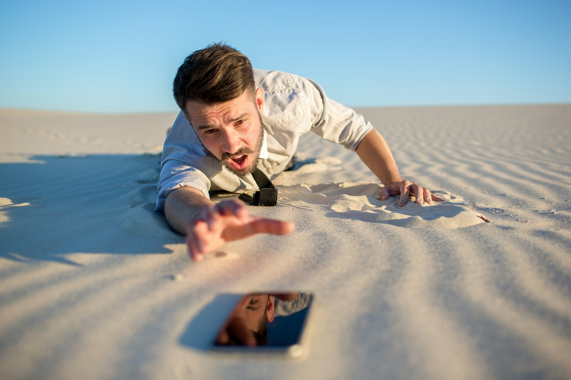 Poor signal. businessman searching for mobile phone signal in desert