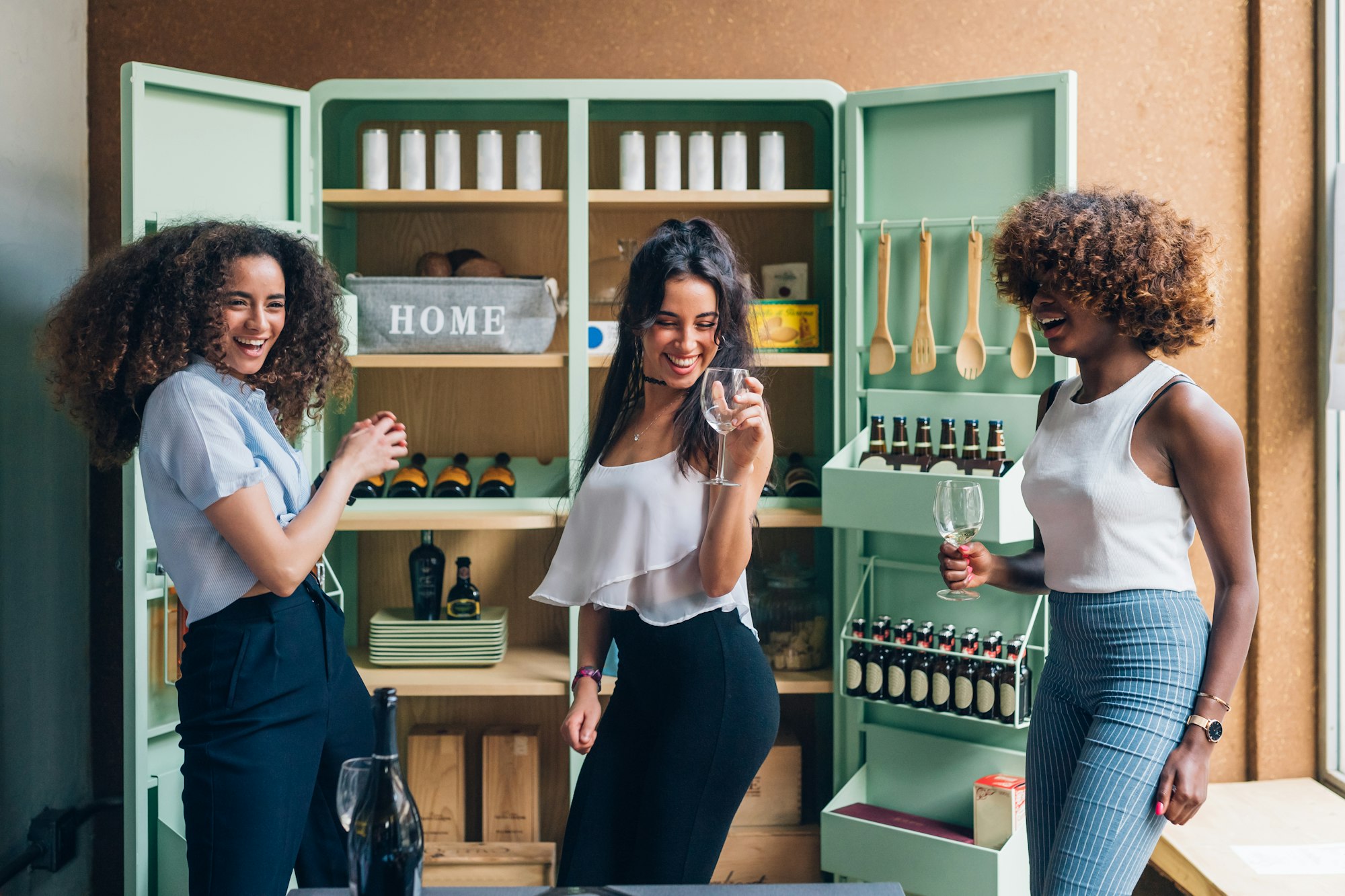 three multiracial women celebrating and dancing in modern pub