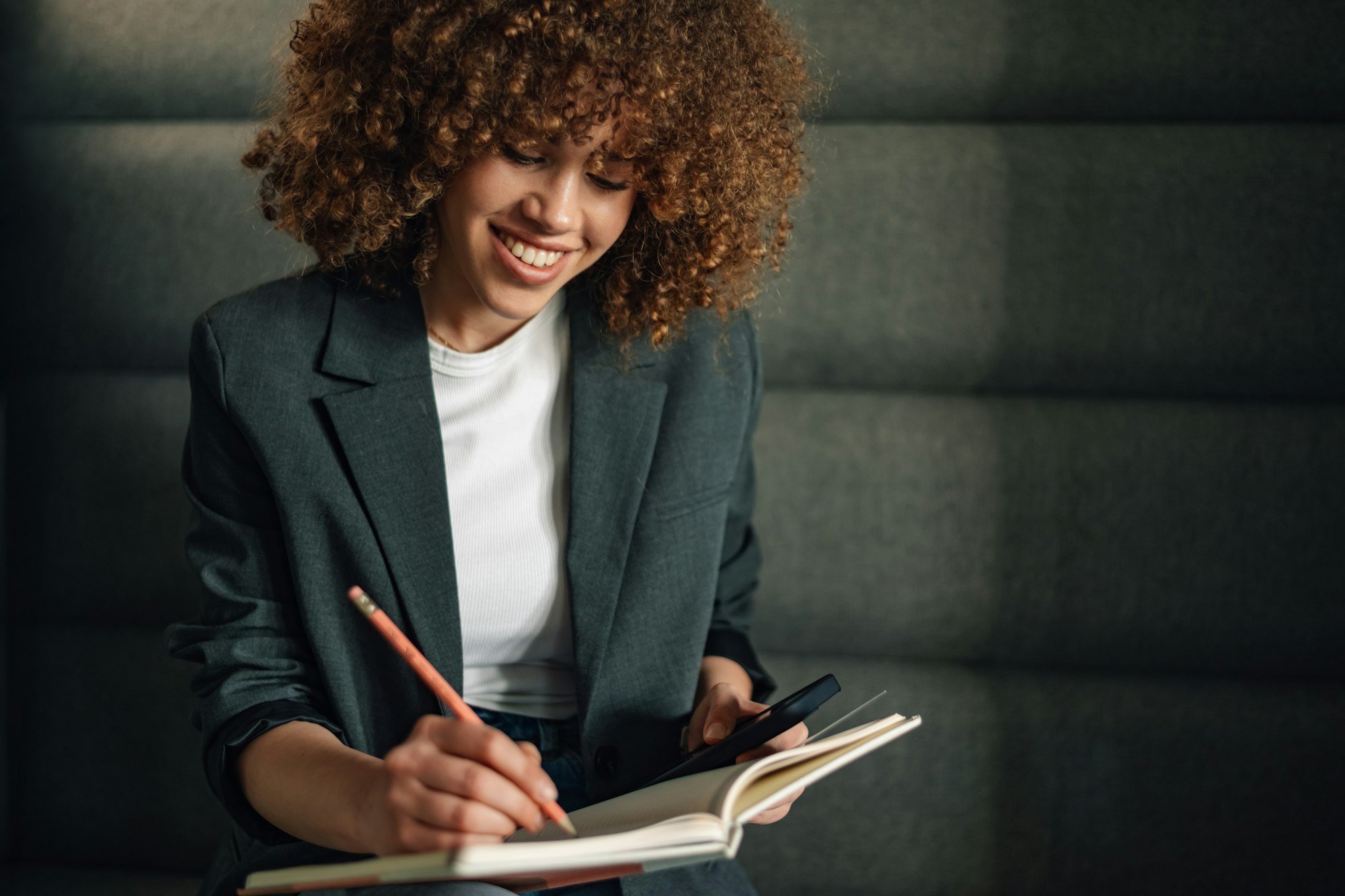 Young businesswoman writing down notes and information in textbook.