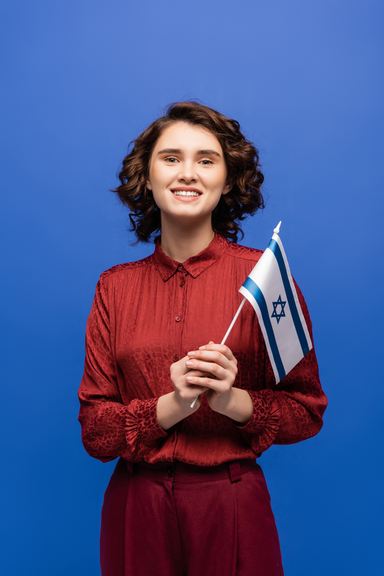 cheerful teacher of Hebrew language holding flag of Israel isolated on blue