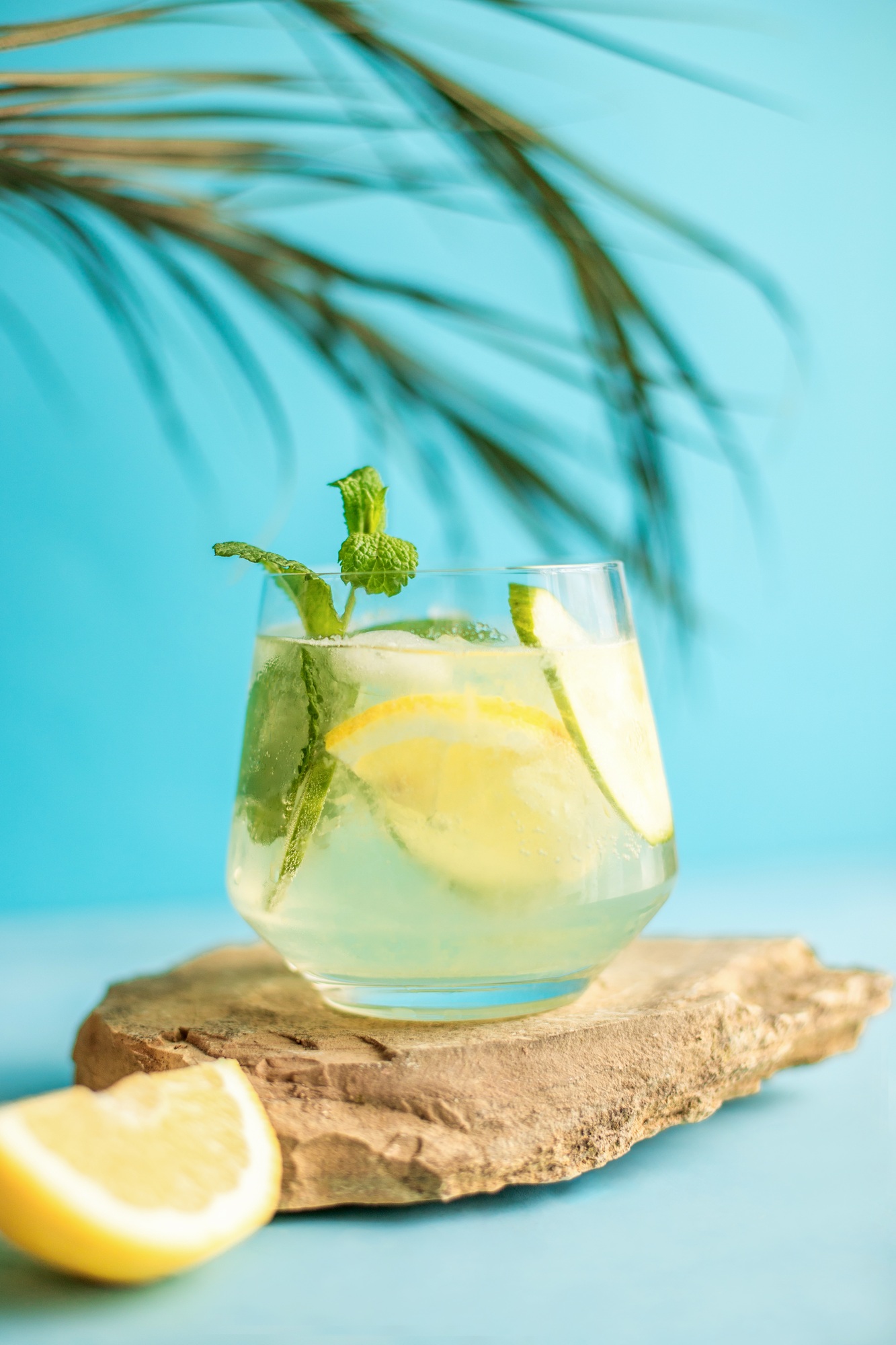 Fresh detox drink with cucumber and lemon slices on a stone platform, with mint. Summer cocktail.