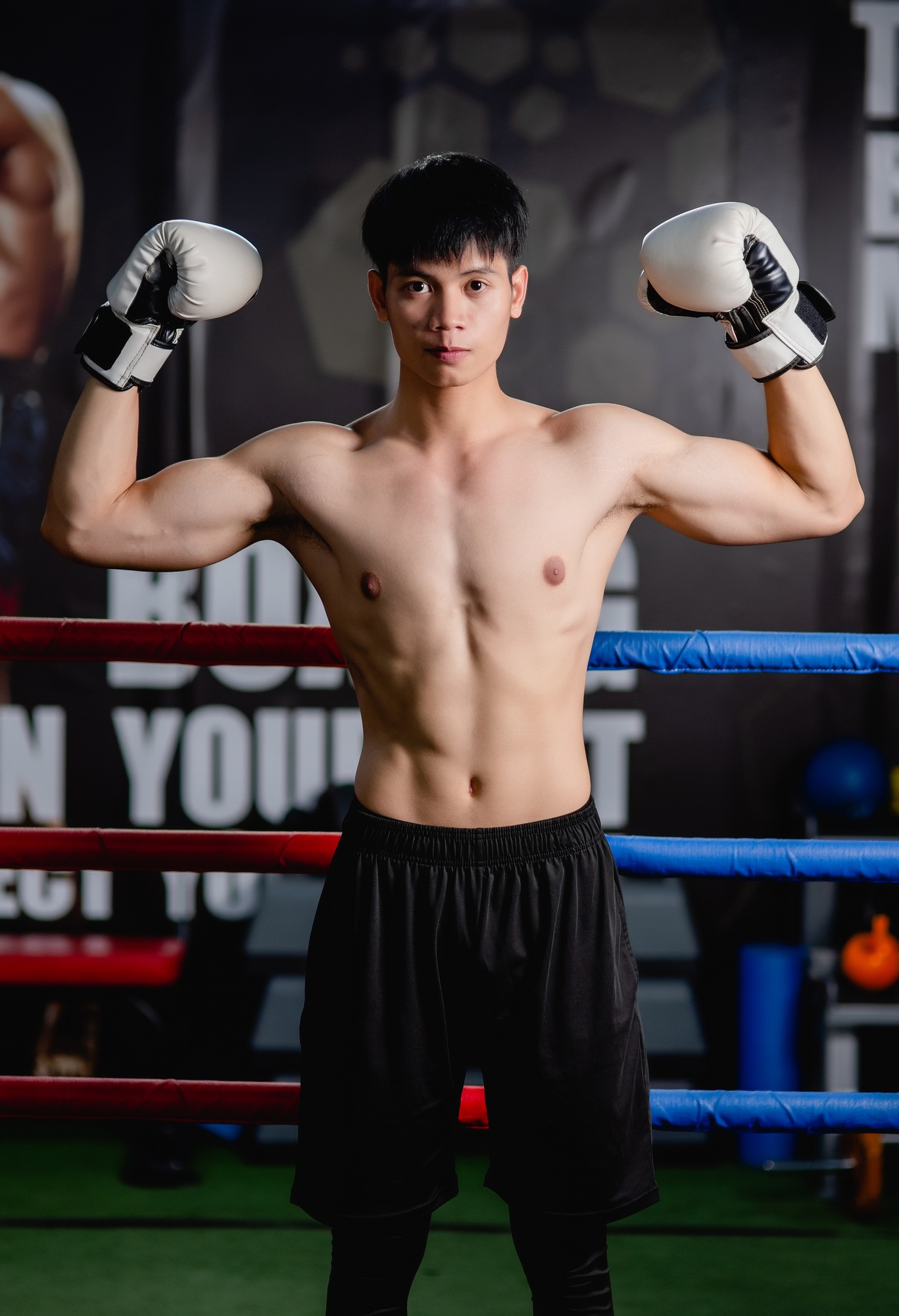 Young man shirtless pose in boxing gloves at fitness gym